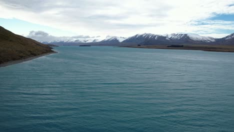 aerial view of lake tekapo with snowy mountain range in the background in south island, new zealand