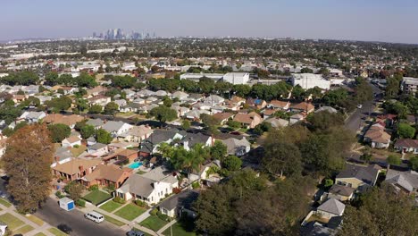 aerial descending shot of a south la neighborhood with downtown los angeles in the background