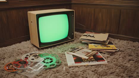 vintage television set with film reels and magazines on carpet