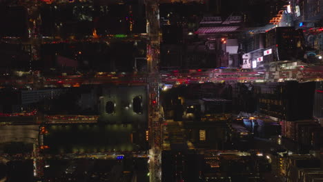 Aerial-birds-eye-overhead-top-down-panning-view-of-blocks-of-buildings-and-streets-in-night-city.-Flashing-and-glowing-colour-light-from-Times-Square.-Manhattan,-New-York-City,-USA