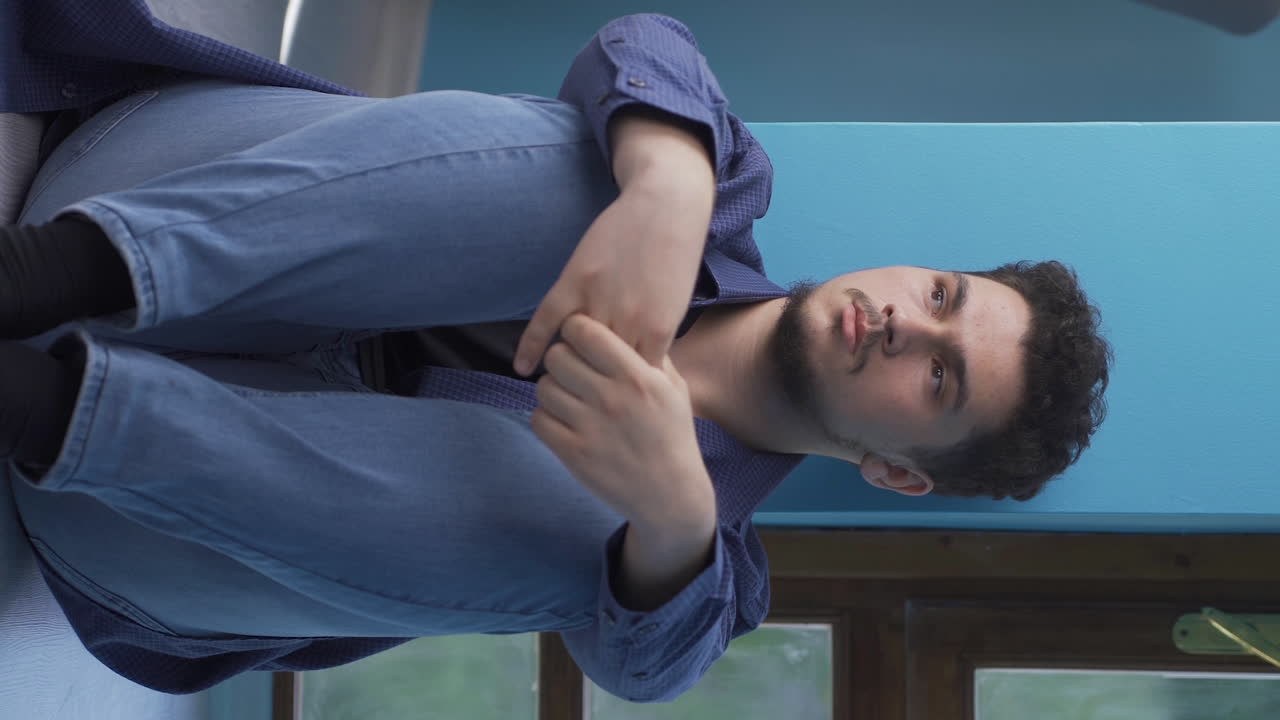 video vertical de un hombre exhausto y pensativo apoyando la cabeza contra la pared.