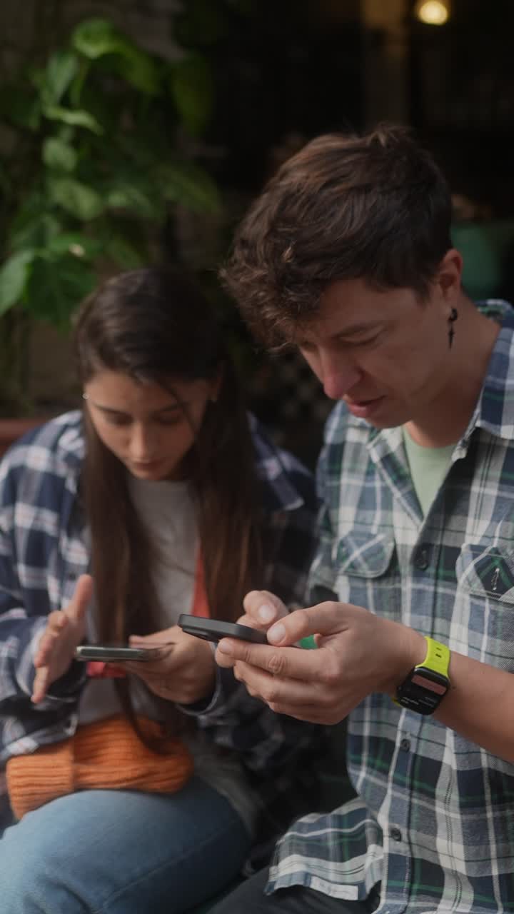 una pareja joven usando teléfonos inteligentes en un café
