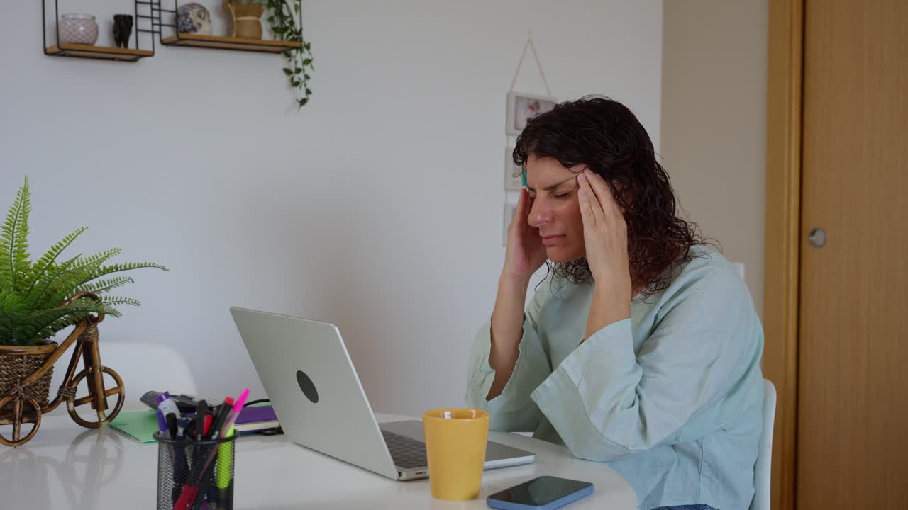 Donna stressata con mal di testa mentre lavora al laptop a casa