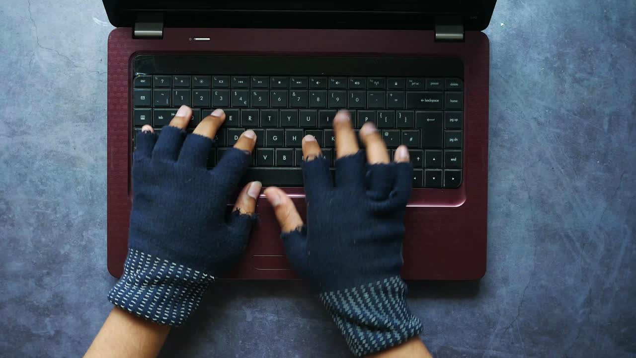 Person Typing on Laptop with Gloves