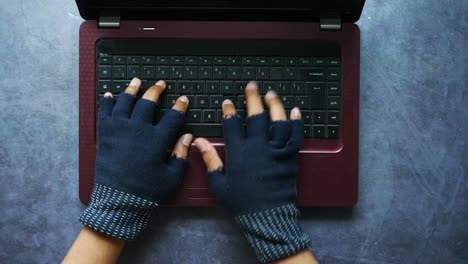 persona escribiendo en una computadora portátil con guantes