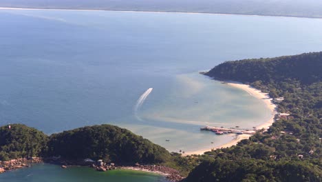 rounded twin islets with boats and beachside on local bay at ilha do mel island, paraná, brazil