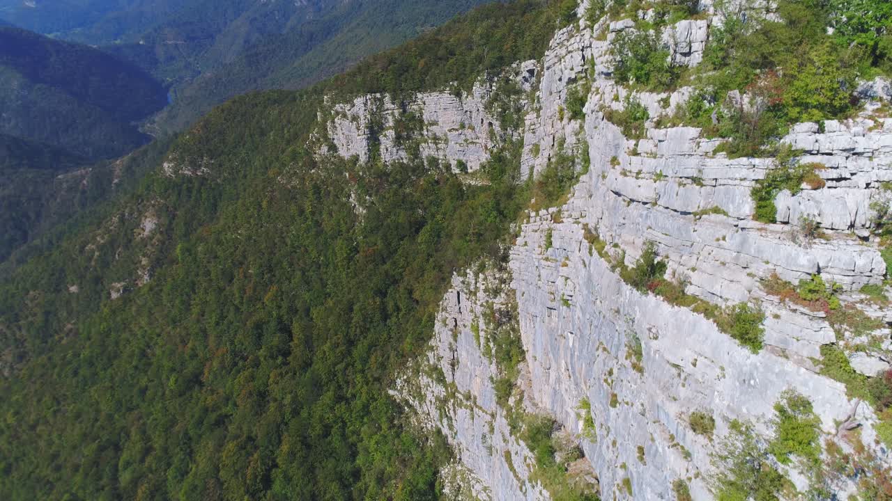 foque aéreo abajo de la pared de piedra y colinas cubiertas de vegetación en el valle de kostel, eslovenia