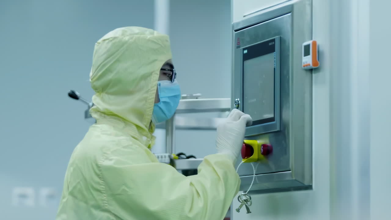 Scientists or Technicians in Sterile Suits Uniform Check Data on high-tech control panel for automation in Pharmaceutics biopharmaceuticals Manufacturing Laboratory workshop