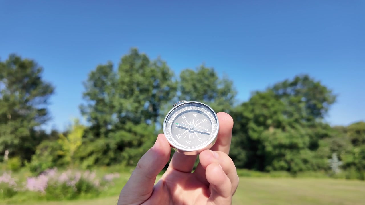 Hand Holding Compass in Sunny Green Park