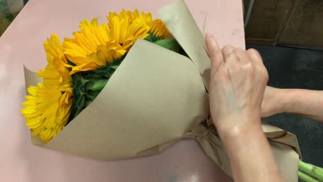 A-local-florist-wrapping-a-bouquet-of-fresh-cut-sunflowers-with-brown-butcher-paper-and-tying-it-with-twine