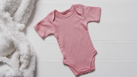 Video-of-pink-baby-grow-and-white-furry-rug-with-copy-space-on-white-background