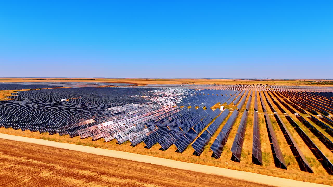 Aerial view of solar power station in desert. Large solar panels cover vast land in a desert area under clear blue sky