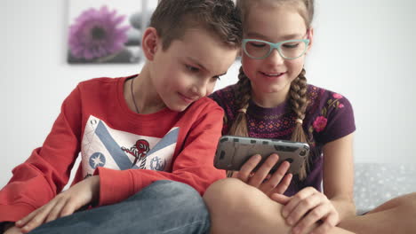 portrait of kids looking at mobile phone at home