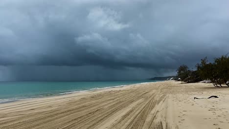 layers and contrasts - 4x4 tracks on the beach reach into the distance as a dark and angry storm hangs over the green pacific ocean