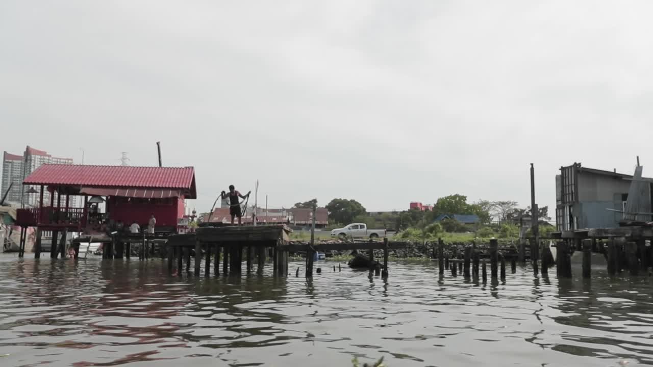 pescador con la red en el muelle en un río en bangkok, tailandia