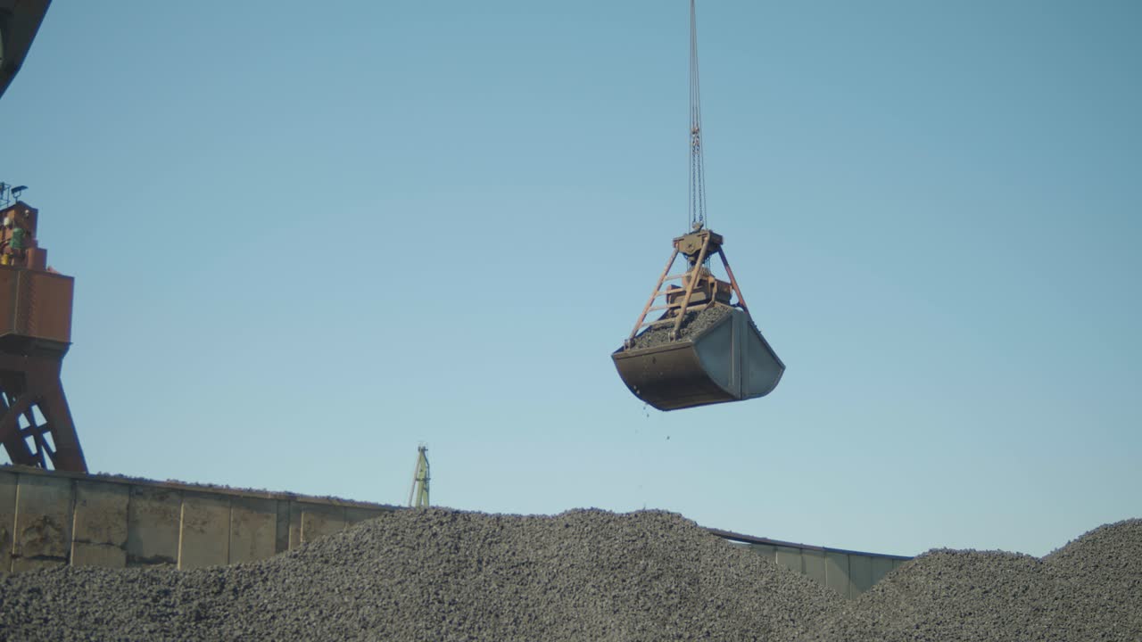 Construction crane moving gravel at gravel yard