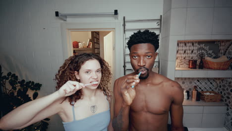 joven pareja multiétnica cepillándose los dientes juntos en el baño