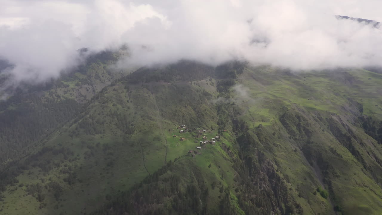 un dron descendente cinematográfico disparó a través de las nubes de un pequeño pueblo en la cima de una montaña en el pueblo de tusheti en georgia