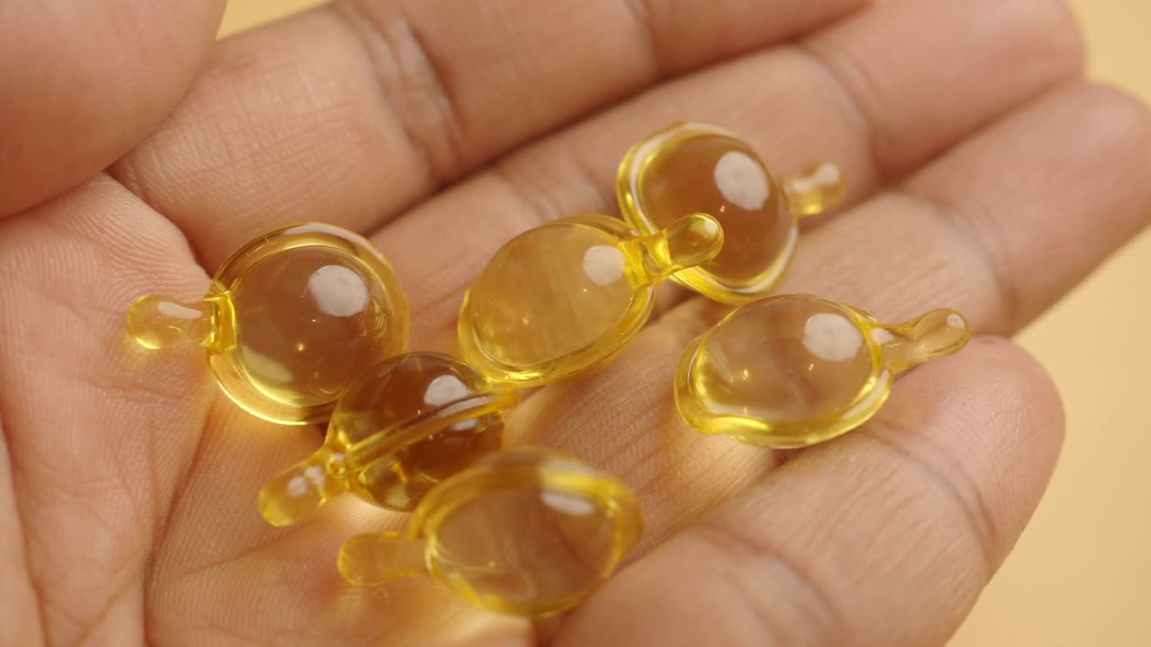 Hand Holding Clear Yellow Skin Care Capsules