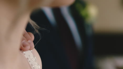 man in suit puts hand on shoulder of bride in light room