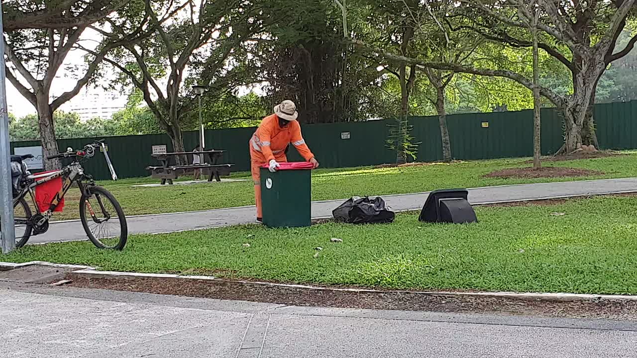 Cleaner with face mask clearing dustbin during Covid-19 lockdown in Singapore, Asia