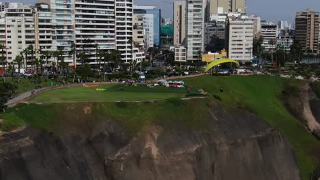 4k video of a flying paraglider over the green coast of the pacific ocean in the miraflores district of lima, peru