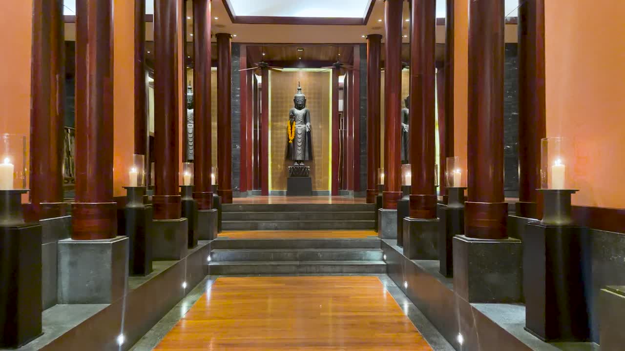 En langsom zoom ind mod en Buddha-statue i en overdådig resortlobby i Phuket med søjler