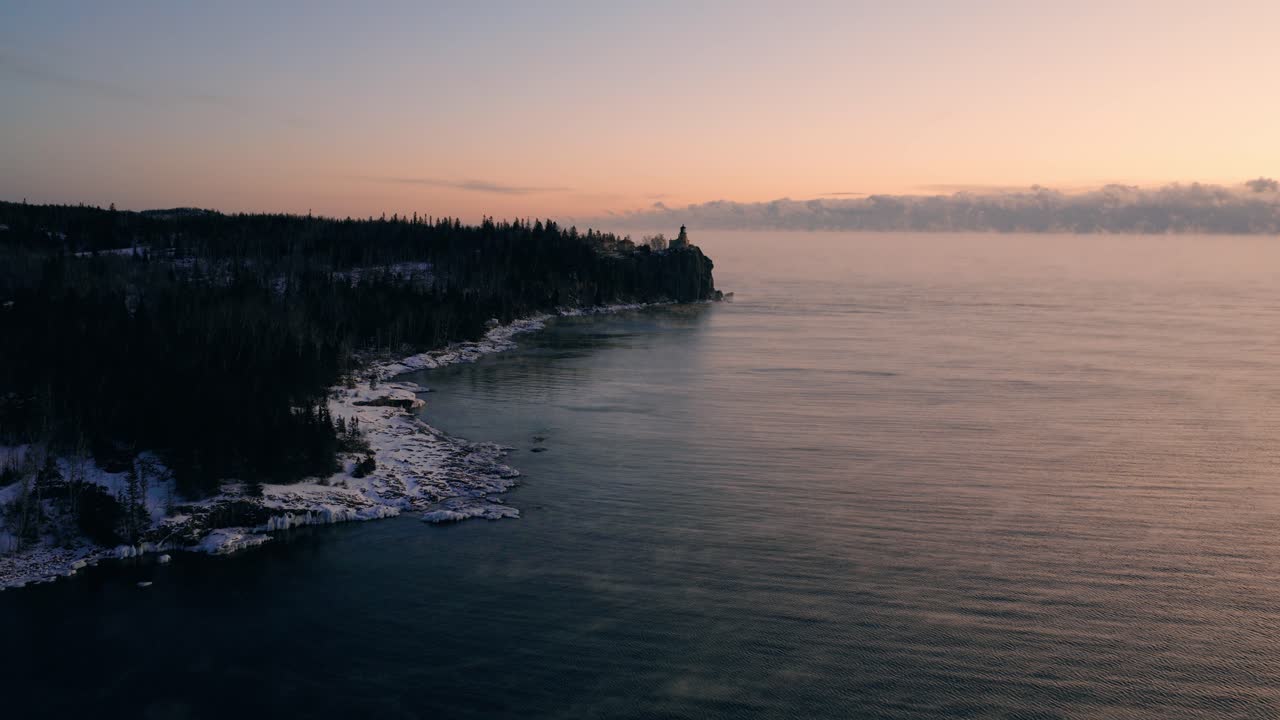 Panoramica aerea del litorale ghiacciato e delle acque blu profonde del Lago Superiore sotto una fredda alba invernale
