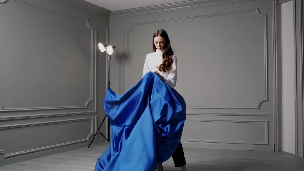 Woman in White Shirt and Black Pants with Blue Fabric