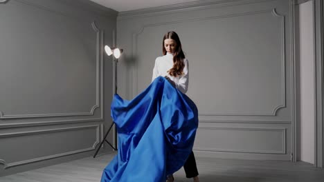 woman in white shirt and black pants with blue fabric