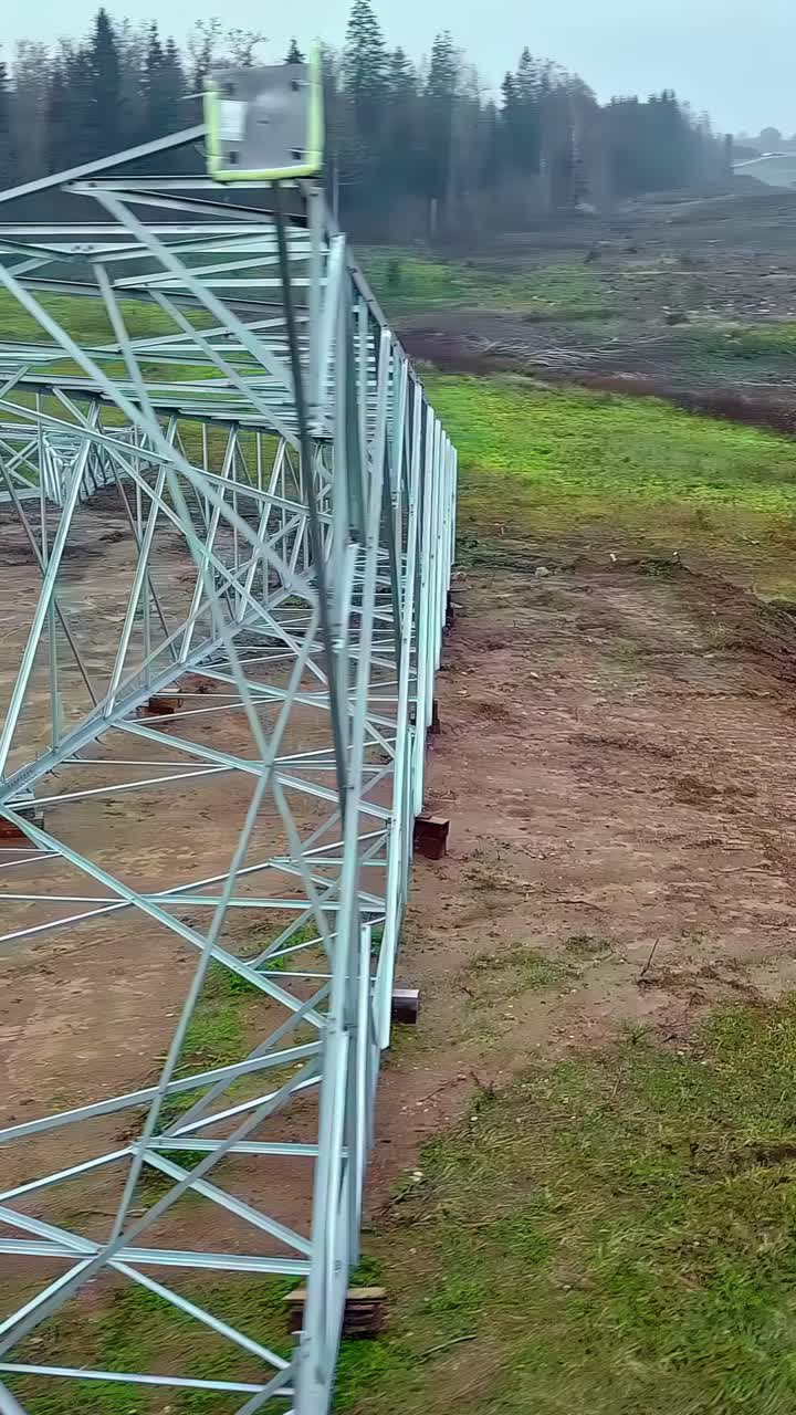 partes de una torre de telecomunicaciones en el suelo antes de levantarla, construcción de infraestructura, vuelo de drones alrededor, bosques cercanos, disparo vertical