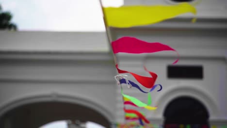 Colorful-textile-flags-garland-outside-white-building-on-windy-day-in-Asia