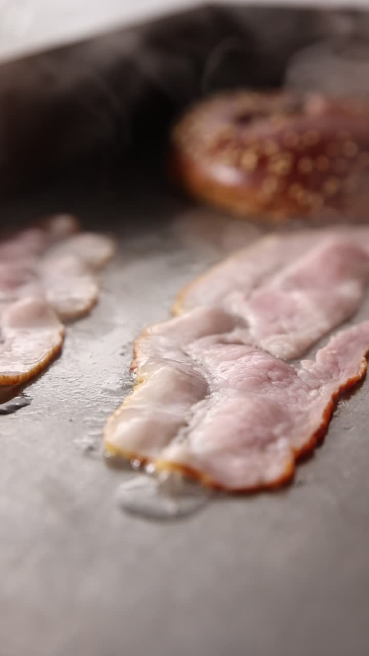 Fette di pancetta che friggono su una piastra calda con vapore