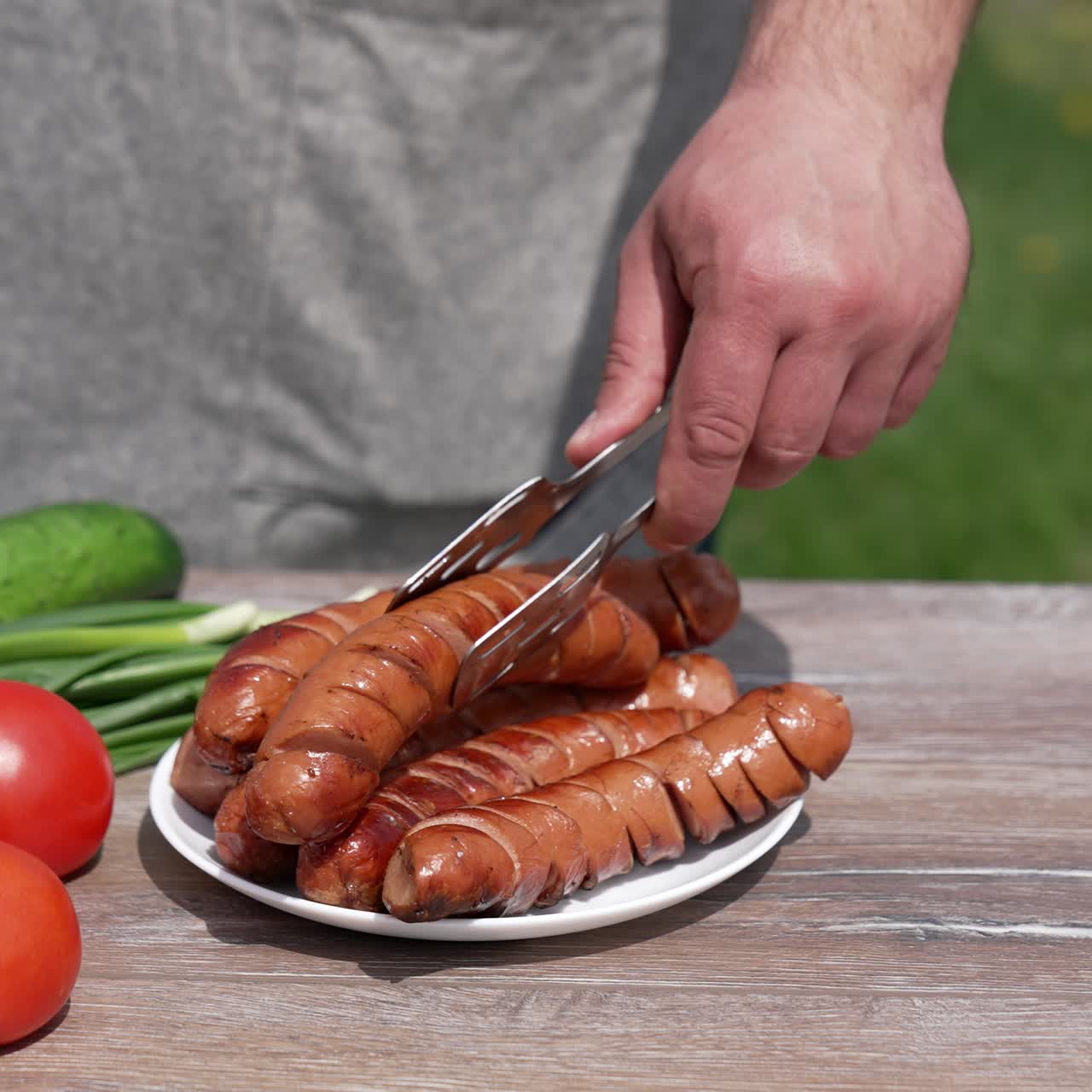 Human hands taking fried juicy sausage. Man prepairing meal for picnic