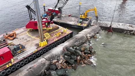 using a grapple, a crane moves pieces of riprap to build up a pier in algoma, wi on lake michigan