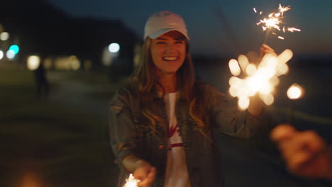 young woman playing with sparklers celebrating new years eve with friend having fun evening with sparkler fireworks sharing celebration at night