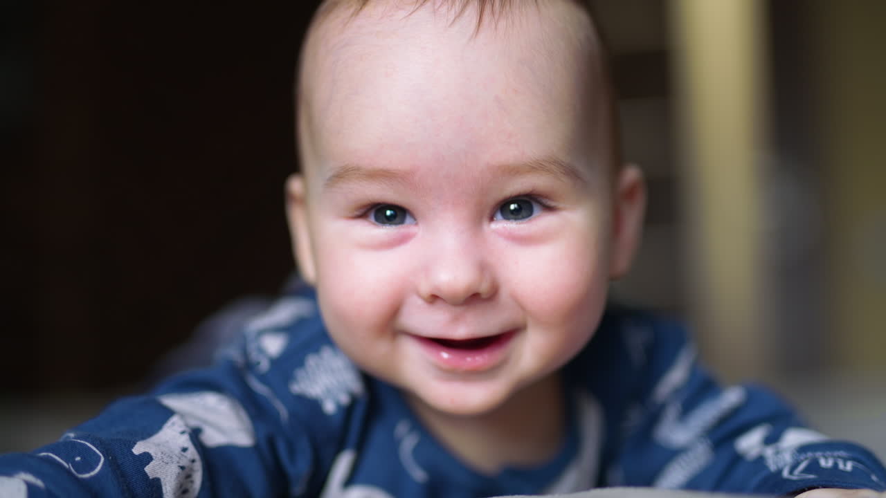 Cute boy looks down with astonishment. Beautiful Caucasian kid smiling with his toothless smile. Close up.