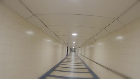 first person running through an empty airport station hall passage