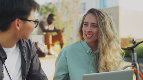 multiethnic female colleagues talking in park while working remotely