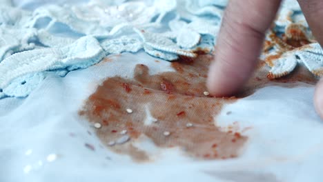 hand checking a sauce stain on a light blue lace dress