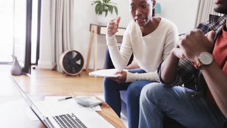serious african american couple using laptop and discussing finance in living room, slow motion