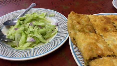 vista de cerca del plato de ensalada junto al plato lleno de mughlai paratha