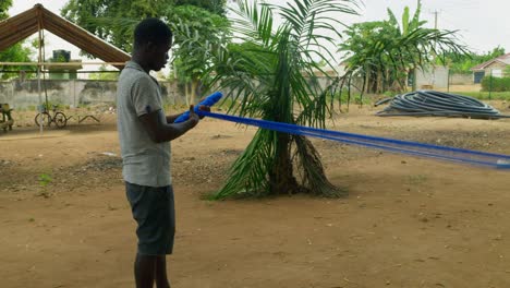 african artisan male rolling up kente handwoven cloth for making fabrics in ghana