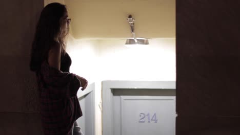 hand-held shot of a woman leaning on a doorway waiting on her friend