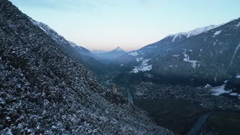 Puesta-De-Sol-En-Un-Valle-Invernal-En-Las-Montañas-Y-Una-Pequeña-Ruina-Al-Borde-Del-Bosque