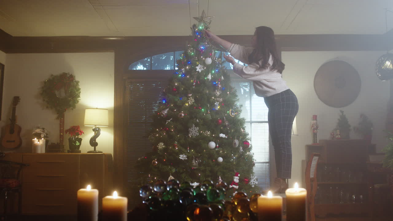 Woman decorating a Christmas tree in a cozy, festive room