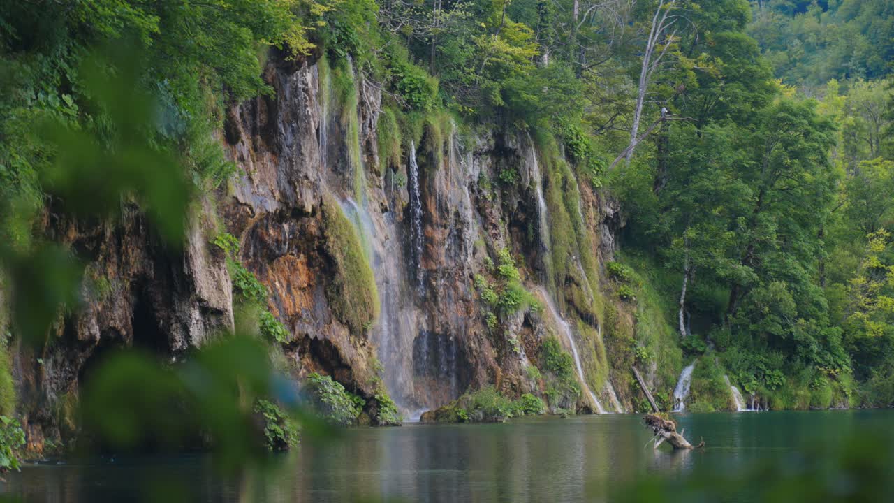 Beberapa air terjun mengalir dari tebing batu kapur ke danau yang tenang di Danau Plitvice, Kroasia.