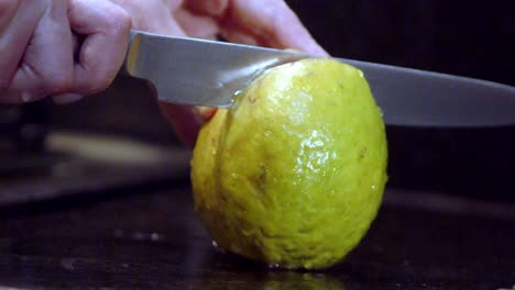 cortando cuidadosamente verticalmente por el centro de la fruta de guayaba