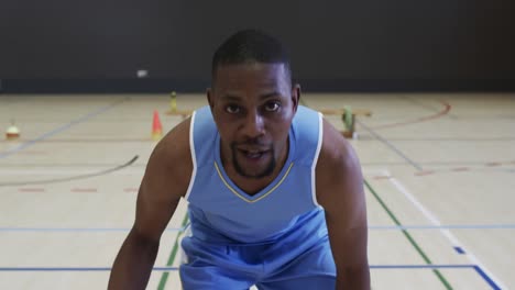 portrait of african american male basketball player playing in indoor court, in slow motion