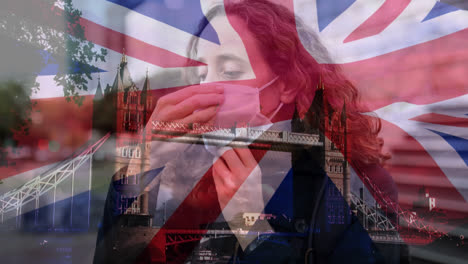 bandera británica ondeando sobre una mujer con una máscara facial contra el paisaje urbano